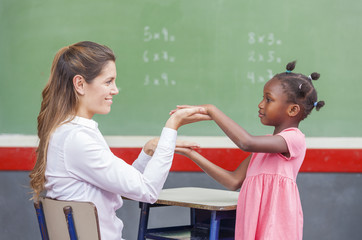 Female teacher with african child at chalkboard. School concept