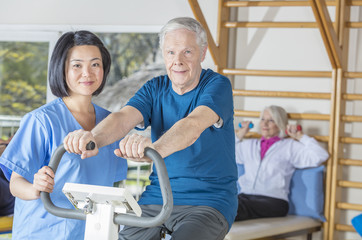 Obraz premium Elderly people in rehab clinic making gymnastics with the help of nurses