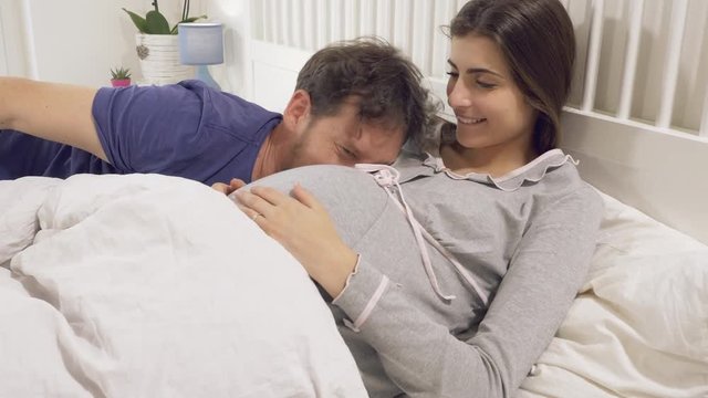 Romantic couple touching pregnant belly talking about names