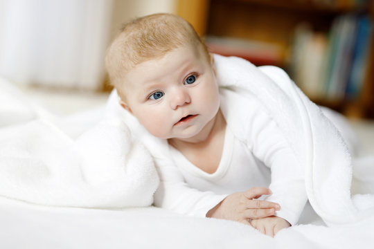 Baby girl wearing white towel or winter overal in white sunny bedroom