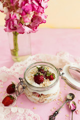 Oatmeal in a jar with strawberries and coconut on a pink background
