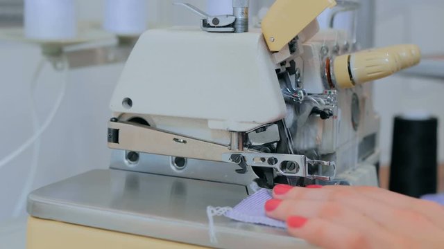 Professional tailor, seamstress using overlocking sewing machine. Fashion and tailoring concept