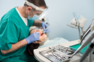 Different professional dental devices, on the blurred background dentist is treating patient in...