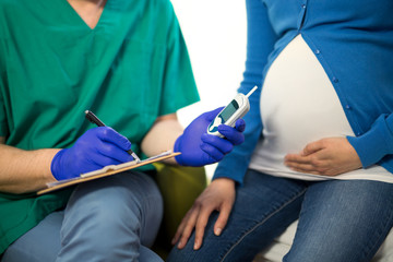 Close-up of a pregnant woman having her blood sugar/ glucose checked.