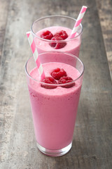 Raspberry smoothie in glass on wooden table
