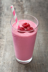 Raspberry smoothie in glass on wooden table

