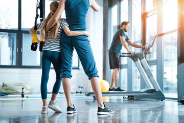 Fototapeta na wymiar Woman with girl looking at handsome man workout on treadmill at gym