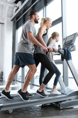 Fototapeta na wymiar Happy family workout on treadmill, side view