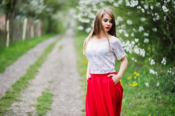 Portrait of beautiful girl with red lips at spring blossom garden, wear on red dress and white blouse.