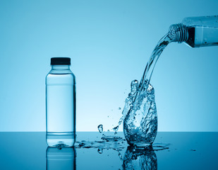 Bottle with creative splashing water in the glass