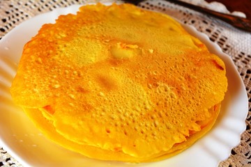 Stack of sweet pancakes decorated on a white plate on a wooden table