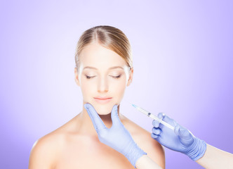 Doctor injecting in a beautiful face of a young woman. Plastic surgery concept.