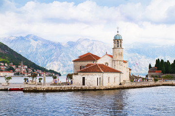 Fototapeta na wymiar Fjord in Adriatic Sea. Our Lady of the Rock island and Church in Perast on shore of Boka Kotor bay (Boka Kotorska), Montenegro, Europe. Kotor Bay is a UNESCO World Heritage Site