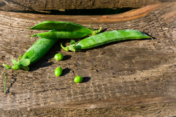 Fresh green pods and peas on a wooden background