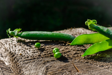 Fresh green pods and peas on a wooden background