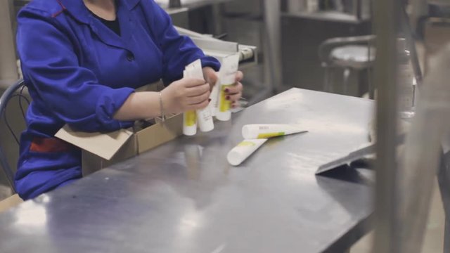Woman sorts and puts the tubes in the box at the factory