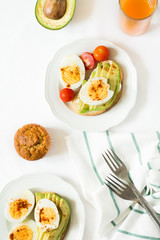 Healthy breakfast: toasts with avocado slices, tomato, paprika and eggs on white tableware. Selective focus