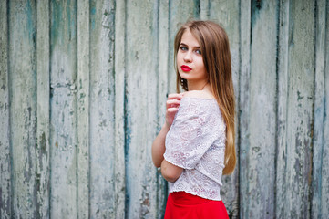 Portrait of beautiful girl with red lips against wooden background, wear on red dress and white blouse.