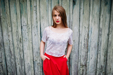 Fototapeta premium Portrait of beautiful girl with red lips against wooden background, wear on red dress and white blouse.