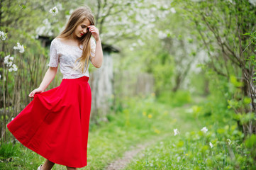 Portrait of beautiful girl with red lips at spring blossom garden, wear on red dress and white blouse.