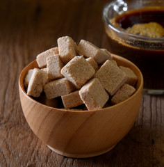 Sugar cubes in wood bowl , coffee background