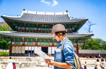 Young woman tourist with map in hand on the background of Asian architecture, travel to Korea,...