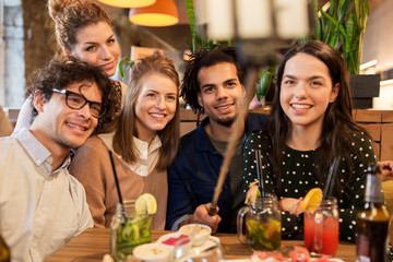 friends taking selfie by smartphone at bar or cafe