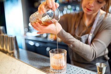 bartender with glass and jug preparing cocktail