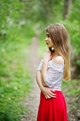 Portrait of beautiful girl with red lips at spring blossom garden, wear on red dress and white blouse.