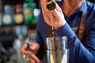 bartender with shaker preparing cocktail at bar