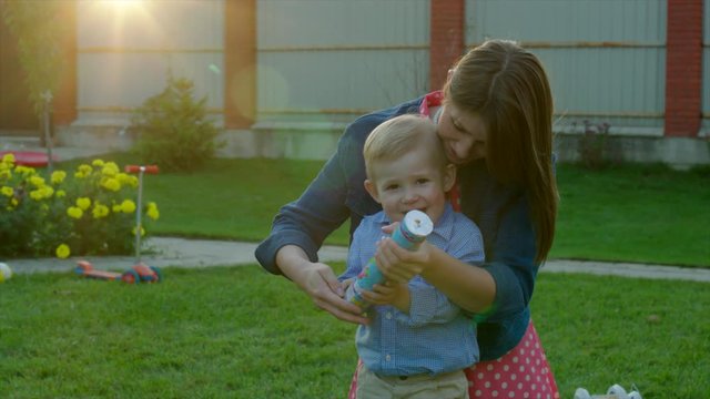 Mom and son exploding party cracker and watching confetti at sunset