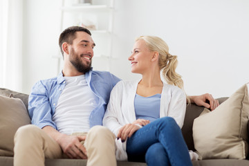 smiling happy couple sitting on sofa at home