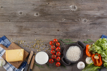 Ingredients for Italian dish. Parmesan cheese, rice and fresh vegetables. On an old wooden background.