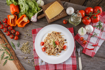 Porridge with vegetables in Italian. Risotto with vegetables. Still life with a dish and fresh vegetables on a wooden background. Rustic