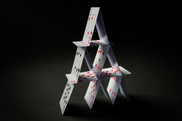 house of playing cards over black background