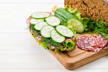 Bread and a sandwich with salami and fresh cucumber