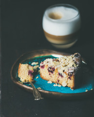 Dessert and coffee. Piece of lemon, ricotta, almond and raspberry gluten-free cake and glass of latte over dark wooden background, selective focus