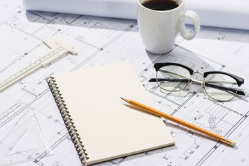 Construction projects. Planning. Open blueprints with a pencil and notebook.