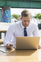 Handsome blonde business man working on laptop outdoor