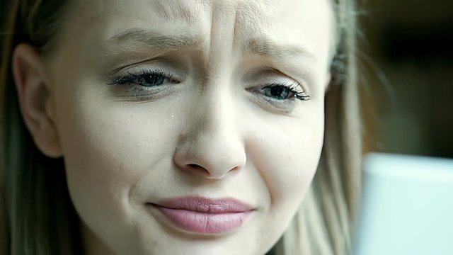 Girl crying and wiping tears while looking on smartphone, steadycam shot
