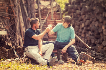 Two male woodcutters having a drink after work