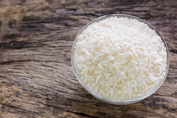 raw thai jasmine rice in a glass bowl on old wooden background with copy space for text