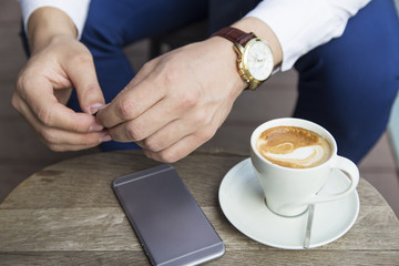 Close up of business man hands with cup of coffee and phone