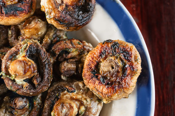 Whole mushrooms roasted on a grill with spices of golden color.