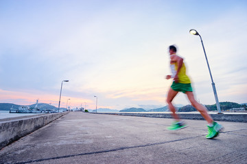 Sports lifestyle. Jogging outdoors. Man running on the sea pier. Motion blur.