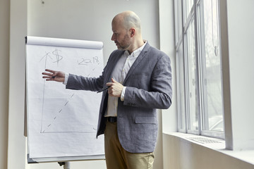 Bald Businessman Standing and Pointing at Something