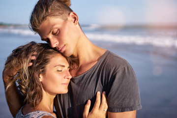 Fototapeta na wymiar Love and romance. Honeymoon on the sea shore. Beautiful loving couple embracing on the beach.