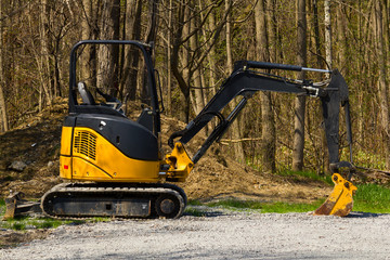 Virginia, Ontario - April 28, 2016: Small Deere excavator parked at the edge of the forest