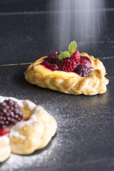 Vanilla Cream and Fruit Berry Puff Pastry Dessert Sprinkled with Powdered Sugar on Dark Background