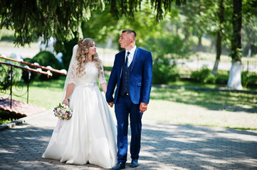 Happy wedding couple in love near small bridge at park on sunny day.